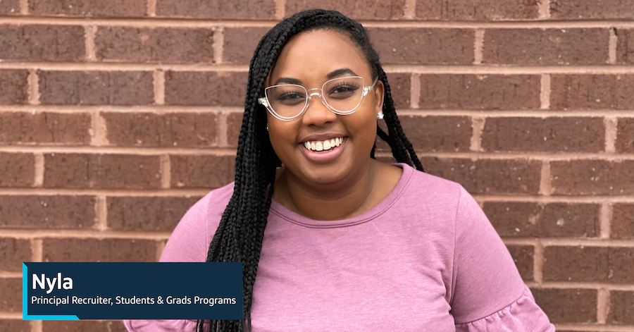 Capital One associate Nyla, Principal Recruiter, Students & Grads Program, stands against a brick wall and smiles